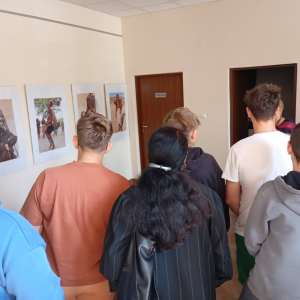 Uczestnicy oglądają zdjęcia z wystawy „Namibia – serce Afryki” rozwieszone na holu w bibliotece.