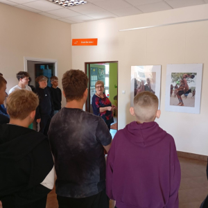 Uczestnicy oglądają zdjęcia z wystawy „Namibia – serce Afryki” rozwieszone na holu w bibliotece.