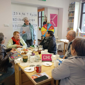 Bibliotekarka czyta pytanie do grupy seniorów.