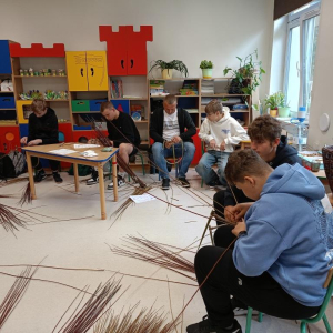Grupa chłopców wykonuje pierwszy etap kosza, wśród nich siedzi pan prowadzący.