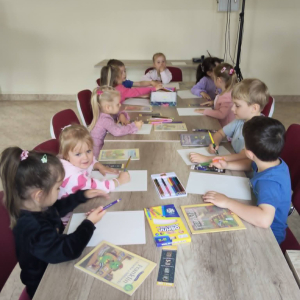 Dzieci siedzą przy stołach i rysują