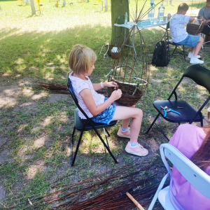 Dziewczynka wyplata koszyk wiklinowy.