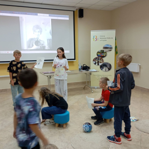 Chłopiec z dziewczynką prezentują swoje prace grupie uczestników