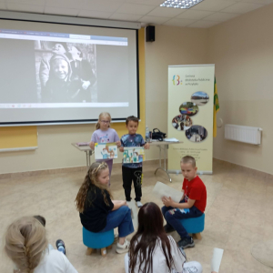 Dwoje dzieci prezentuję swoje prace grupie uczestników