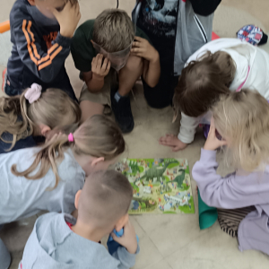 Dzieci siedzą w okręgu,przed nimi leży kolorowa plansza do gry.