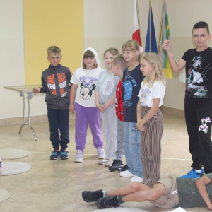 Uczestnicy zajęć pozują do wspólnego zdjęcia, jeden z chłopców leży na podłodze.
