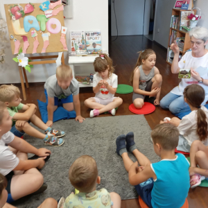 Bibliotekarka pokazuje grupie dzieci przykłady pocztówek.