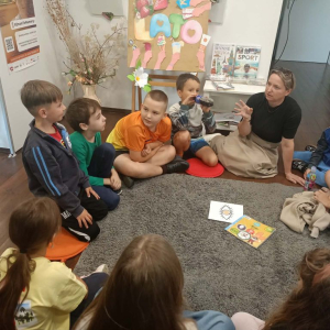 Dzieci podczas zajęć wakacyjnych rozmawiają z bibliotekarką o zmyśle wzroku
