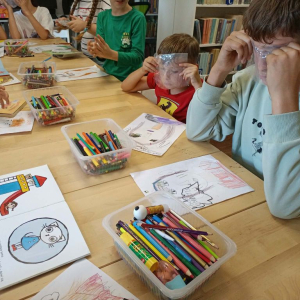 Zajęcia kreatywne dla dzieci w bibliotece – uczestnicy patrzą przez kawałki folii