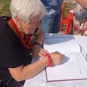 Kobieta wpisuje życzenia do Parafialnej Księgi Pamiatkowej 