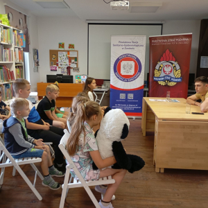 Grupa dzieci na spotkaniu edukacyjnym ze strażakiem i przedstawicielką sanepidu