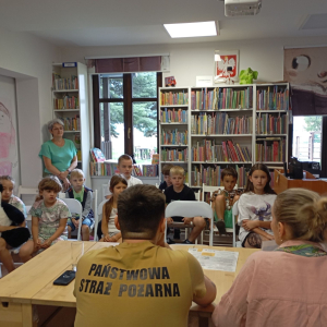 Grupa dzieci na spotkaniu edukacyjnym ze strażakiem i przedstawicielką sanepidu