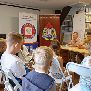 Grupa dzieci na spotkaniu edukacyjnym ze strażakiem i przedstawicielką sanepidu
