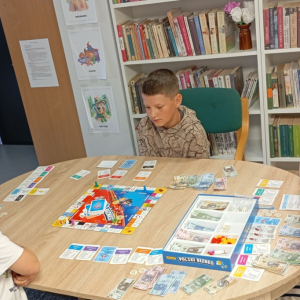 Troje dzieci gra z bibliotekarką w planszówkę