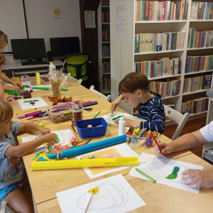 Grupa dzieci przy stole podczas zajęć w bibliotece