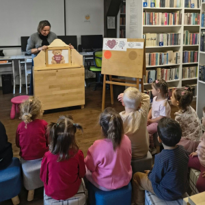 Bibliotekarka zapowiada teatr kamishibai przed grupą maluchów
