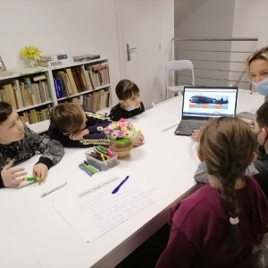 Dzieci z opiekunem oglądają stronę biblioteki