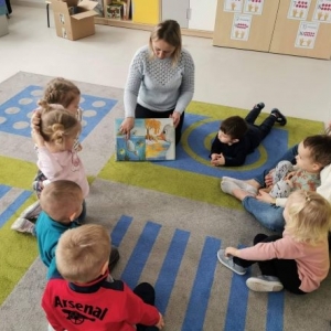 Prowadząca pokazuje dzieciom obrazki w książce