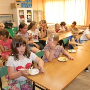 Siedzące w ławkach dzieci, na stołach talerze