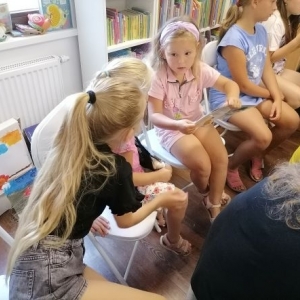 Dzieci siedzą razem podczas zajęć w bibliotece