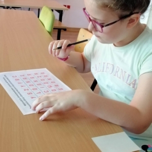 Chłopiec siedzi nad kartką z ołówkiem w ręku