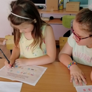 Dziewczynka obserwuje koleżankę która pisze po kartce