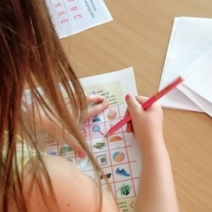 Dziewczynka siedzi pochylona nad książką z kolorowymi obrazkami