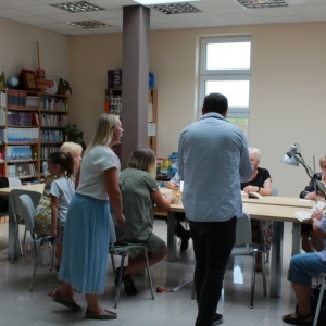 Kadr z kręcenia spotu o bibliotece. Przy stole osoby biorace udział w nagrywaniu.