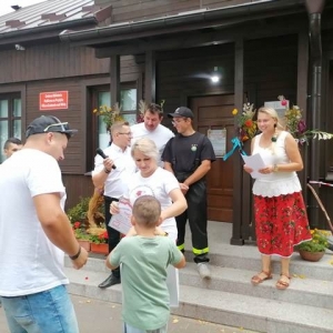 Uczestnicy Dożynek stoją razem przed budynkiem biblioteki