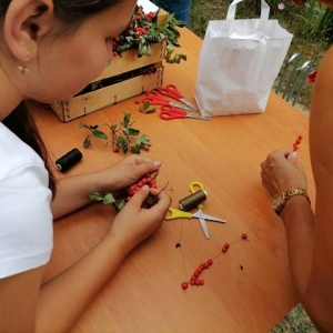 Dziewczynka robi naszyjnik z jarzębiny