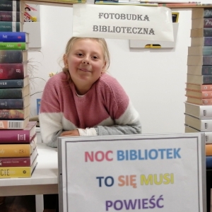 Uśmiechnięta dziewczynka w fotobudce bibliotecznej.