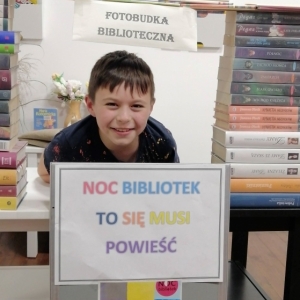 Chłopiec usmiecha się w fotobudce bibliotecznej.