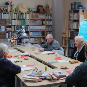 Uczestnicy spotkania literackiego siedzą przy stole i dyskutują.